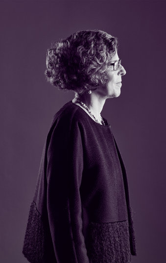 Dr Beatrice, an oncologist, stands facing right in a purple tone