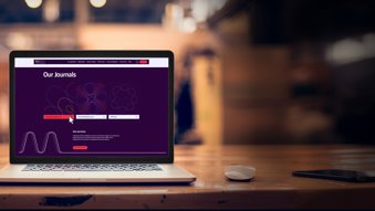 An open laptop on a table, showing the web page "Our Journals"